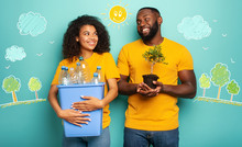 Happy Couple Hold A Plastic Container With Bottles And A Small Tree Over A Light Blue Color. Concept Of Ecology, Conservation, Recycling And Sustainability
