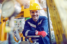 Handsome Caucasian Smiling Unshaven Worker In Protective Uniform Leaning On Valve While Standing In Factory.