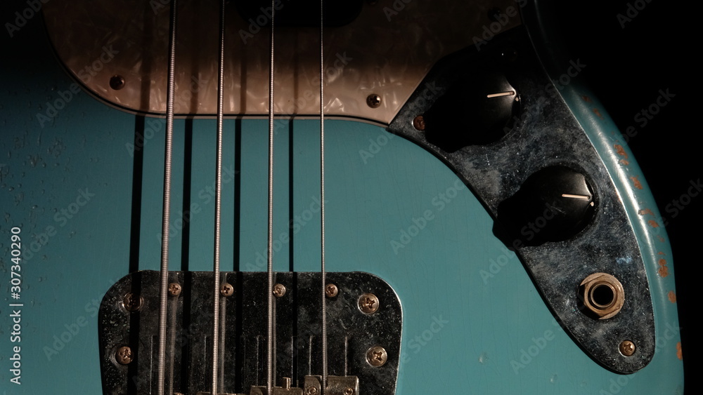 Closeup of Blue Guitar Bass and light coming through on Body Relic with selective focus. - obrazy, fototapety, plakaty 