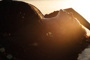 Wall Mural - Sexy woman wearing black tunic is posing on the beach with black sand