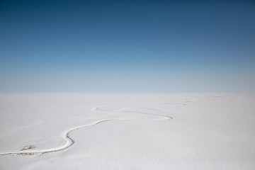 Wall Mural - Amazing Arctic aerial landscape. Top view of the endless snow-covered tundra and the Avtatkuul River. Travel to the far North of Russia. Location place: Chukotka, Siberia, Russian Far East.