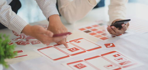 Cropped shot of young professional UX web developer working on smartphone