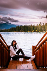 Wall Mural - couple watching sunrise by the lake at Jasper , Lac Beauvert Alberta Canadian Rockies Canada