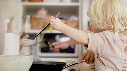 Wall Mural - Small boy with unrecognizable mother indoors in kitchen, making pancakes.