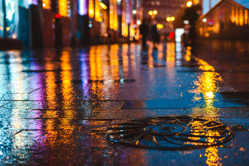 Rainy night in a big city, reflections of lights on the wet road surface.