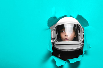 small child in wearing an airplane helmet looking through a hole of paper