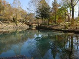 Fototapeta Tęcza - Wide shot of colorful trees in autumn reflected in the clear waters of a blue spring