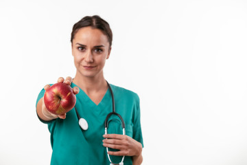 Wall Mural - Beautiful female doctor in green uniform. Portrait of nurse holding an apple. 