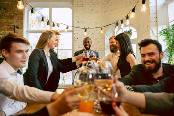 Wall Mural - Happy co-workers celebrating while company party and corporate event. Young caucasian people in business attire cheering, laughting. Concept of office culture, teamwork, friendship, holidays, weekend.