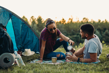 Wall Mural - couple drinking coffee, camping by the river outdoor