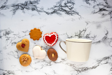 Wall Mural - White cup of coffee tea and ginger biscuits heart shape cookies on marble background. Valentine's day greeting card. Flat lay, top view, copy space