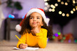 © Prostock-studio - Wistful little afro girl thinking about letter to Santa Claus