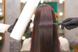 Straight and shiny hair after lamination. Hairdresser demonstrates the result of keratin hair straightening