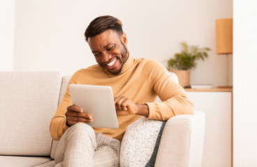 Canvas Print - Black Guy Using Tablet Smiling Sitting On Sofa At Home