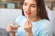 © Pixel-Shot - Young woman taking medicine at home