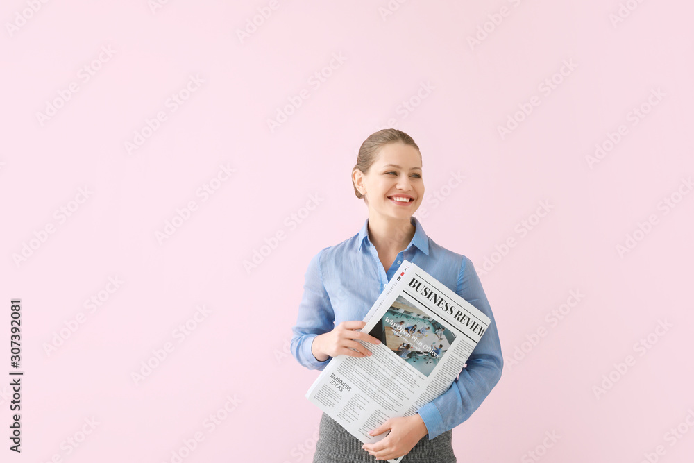 Young businesswoman with newspaper on color background