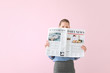 Young businesswoman with newspaper on color background