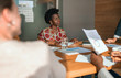 © JonoErasmus - Beautiful young confident professional black african millennial business woman in boardroom meeting. Wearing traditional clothing