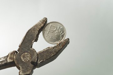 coin denomination of one Russian ruble in old rusty pliers, the concept of the crisis in Russia and sanctions against the Russian economy