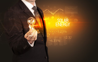 Businessman holding lightbulb with SOLAR ENERGY inscription, Business technology concept