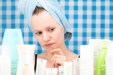 Portrait of girl without makeup in bathroom surrounded by cosmetics