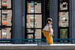 © Manuel Ruiz/ADDICTIVE STOCK - Side view of trendy happy female in wireless headphones and bight yellow clothes with backpack walking against facade windows with reflection of modern building while listening to music in sunlight