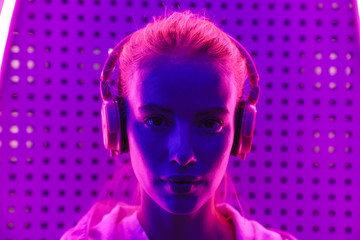 Poster - Image of woman listening to music with headphones over neon illumination