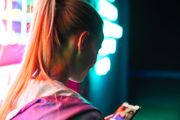 Poster - Image of beautiful woman holding smartphone over neon text sign