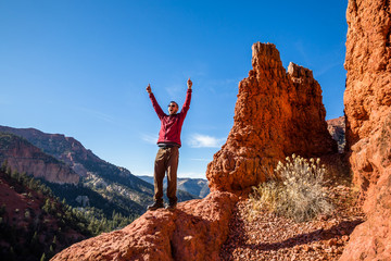 excited man celebrating hiking in the red rock formations of southern utah.