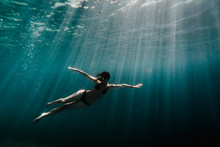 Low Angle View Of Woman Swimming Underwater In Ocean