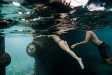 Couple Swimming Underwater Close To Old Boat