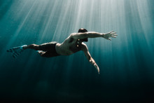 Low Angle View Of Man Swimming Underwater In Ocean