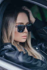 Wall Mural - Stylish blonde woman in black sunglasses in car outdoor