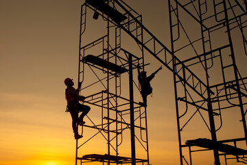 Silhouette  construction worker Climbing scaffolding In order to go up to check the work site