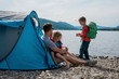 © Cavan Images - family hugging and exploring camping by the water in Norway