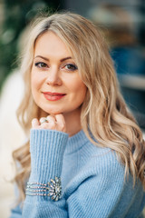 Wall Mural - winter portrait of beautiful woman with blond hair, wearing blue pullover