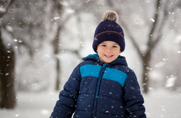 Wall Mural - Adorable, cute boy playing with snow cheerfully. Wintertime, kids activity