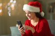© Antonioguillem - Happy woman checks mobile phone at christmas