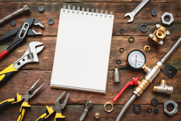 Plumbing flat lay background with copy space. Work tools, pipeline equipment and blank page notepad on plumber workbench. Fix list mockup.