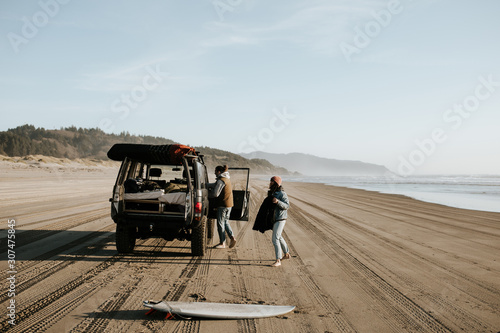 Two people on the beach with their car