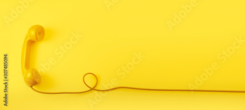 Fotografía A yellow vintage dial telephone handset with yellow background.
