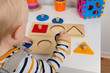 © artursfoto - Child works with Montessori material for fine motor skills, sensory play. Playing children with geometry figures
