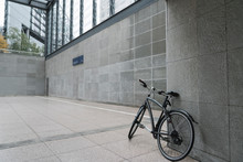 Black Bicycle Leaning Against Wall Of Station Building At Potsdamer Platz, Berlin, Germany