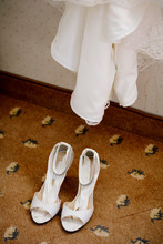 High Angle View Of Sandals On Tiled Floor Under Wedding Dress At Home