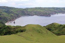 Group Of People Hiking The Mountains Around A Sea Surrounded By Greenery Under A Blue Sky