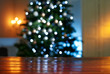© Westend61 - Close-up of wooden table with illuminated Christmas tree in background at home