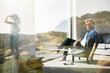 © Westend61 - Casual man sitting in modern home with woman standing in garden