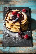 Pancakes With Chocolate Sauce And Various Berries On Table