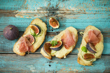 Directly Above Shot Of Baked Cheese Bread With Fig Slices And Ham Served On Wooden Table