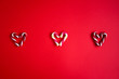 Red and green candy canes on red background. Hearts made out of sugar candy canes. Christmas, holiday concept